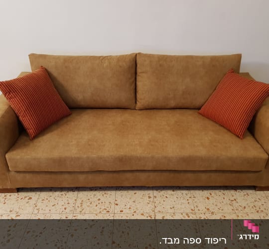 ספה חומה עם כריות כתומות על רצפה מרוצפת